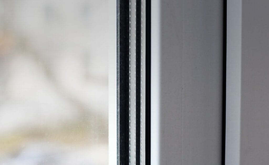 Fenêtres à double vitrage vs vitrage à faible émissivité | Fenomax - Photo d'une personne tenant la poignée d'une fenêtre en PVC